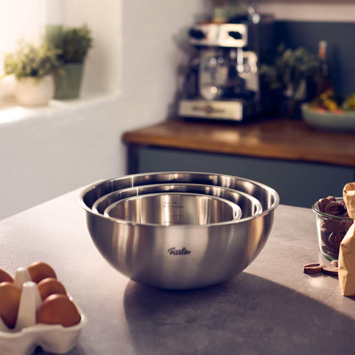 Three stackable Fissler Essential® 16cm bowls, durable and dishwasher-safe, on a countertop with baking ingredients.