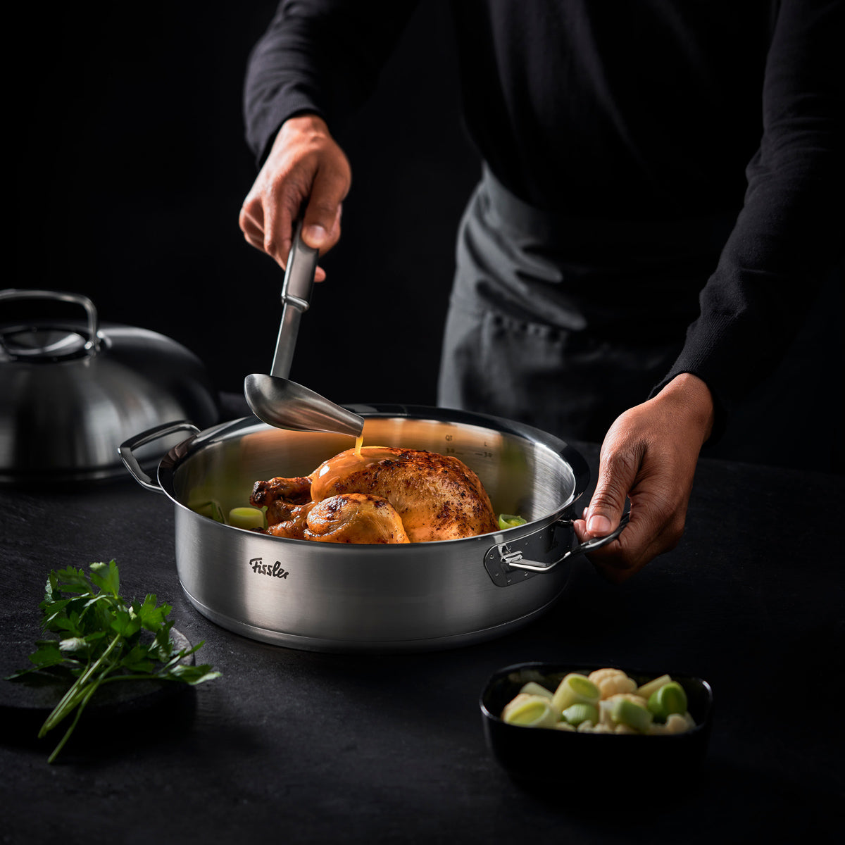 Servieren von gebratenem Hähnchen mit Gemüse aus einem Fissler-Edelstahltopf mit der Original-Profi Collection®-Kelle.