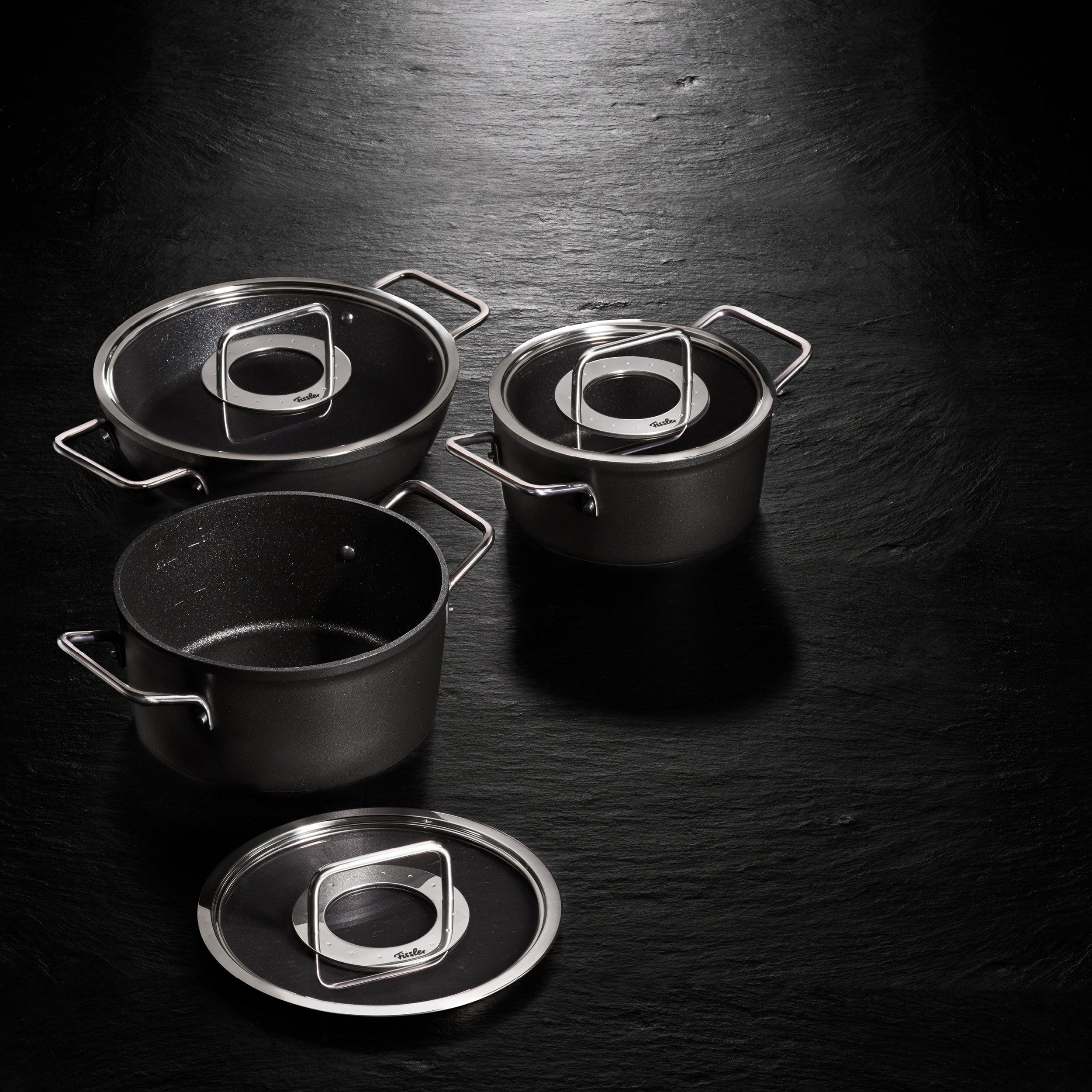 Drei Fissler Adamant® Bratentopf-Töpfe mit Glasdeckeln und silbernen Griffen, die sich durch deutsche Präzision und kratzfestes Design auszeichnen.