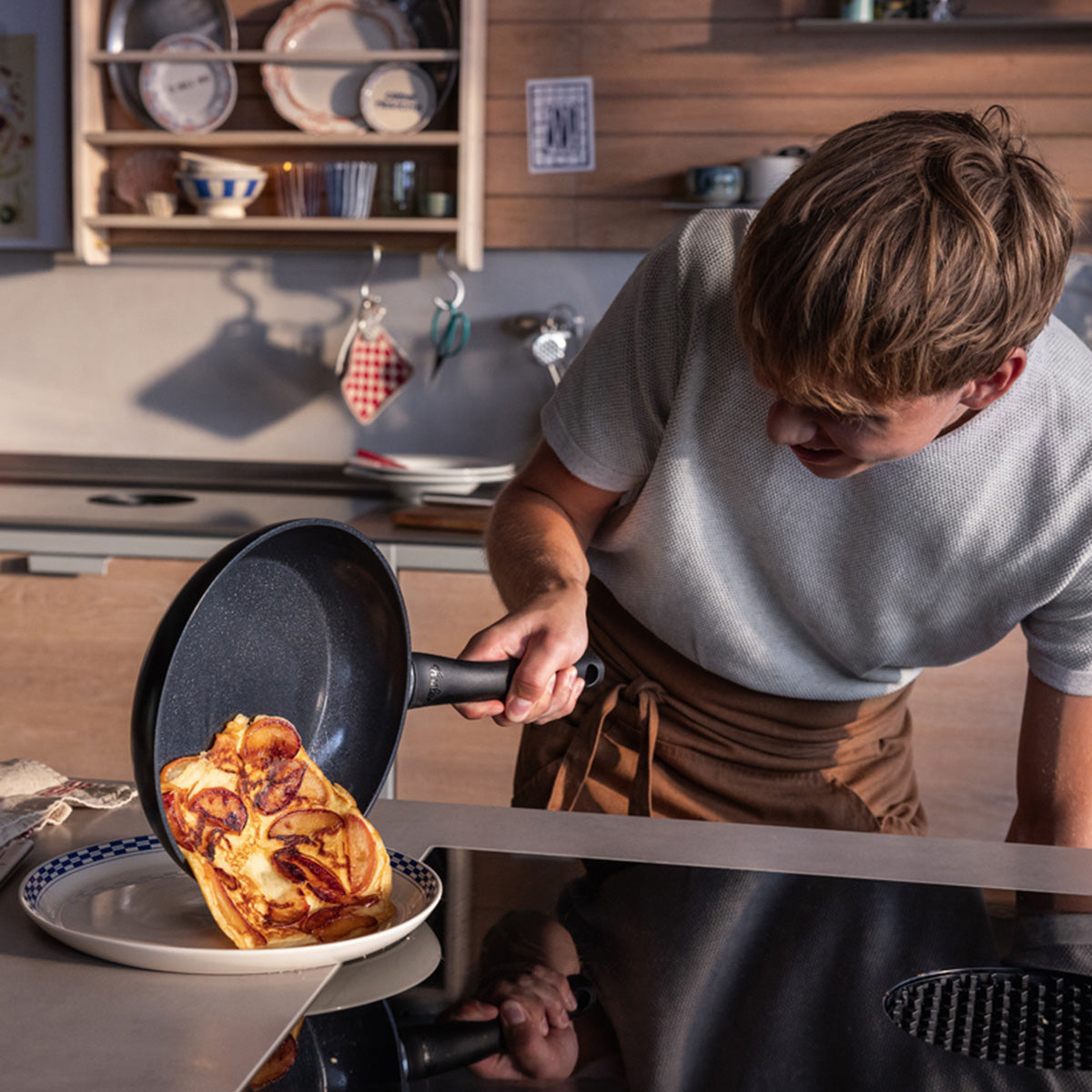 In einer modernen Küche helfen die Fissler Essential® Pfannen (24 cm & 28 cm) dabei, ein gefülltes Omelett auf einen Teller zu gleiten - Qualität made in Germany.