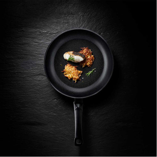 Fissler Levital®+ Classic Pan mit gekochtem Fisch, Kartoffelpuffern und Rosmarin - präzises deutsches Design, modern und funktionell.