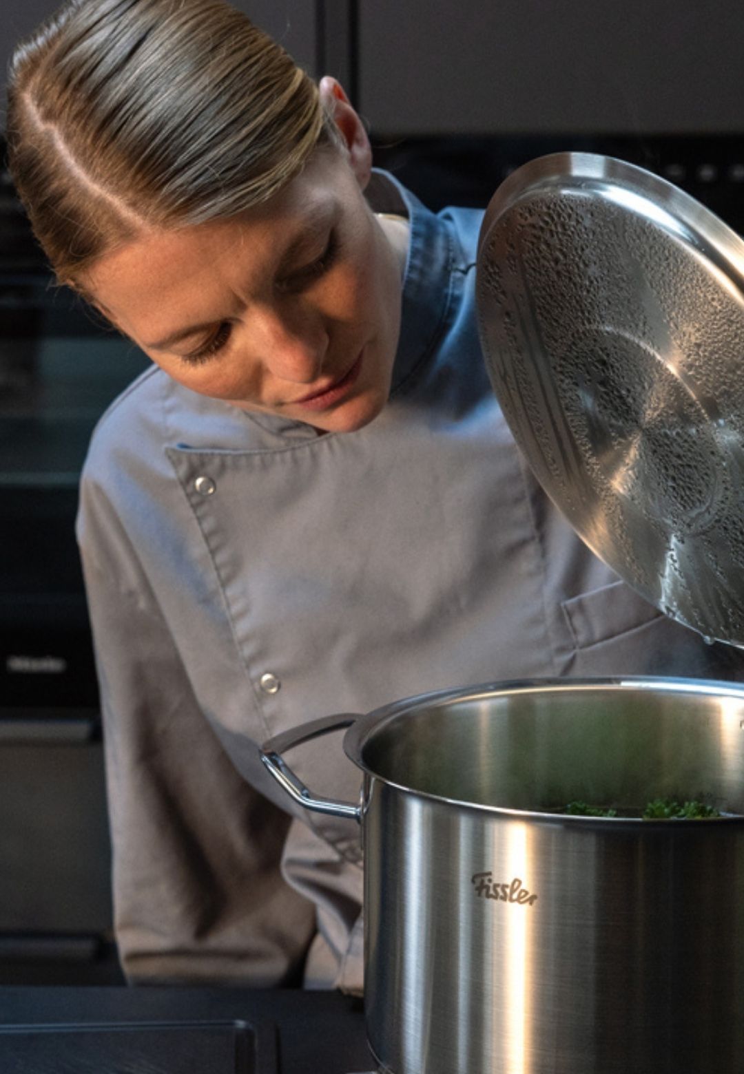 Ein Chefkoch inspiziert einen Fissler-Edelstahltopf in einer modernen Küche, der deutsche Präzision, Langlebigkeit und zeitloses Design unterstreicht.