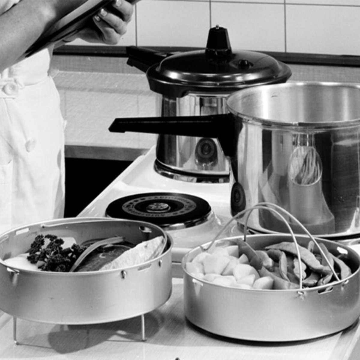 A chef prepares fresh ingredients next to a Fissler stainless steel pot and pressure cooker, demonstrating German precision in the kitchen.