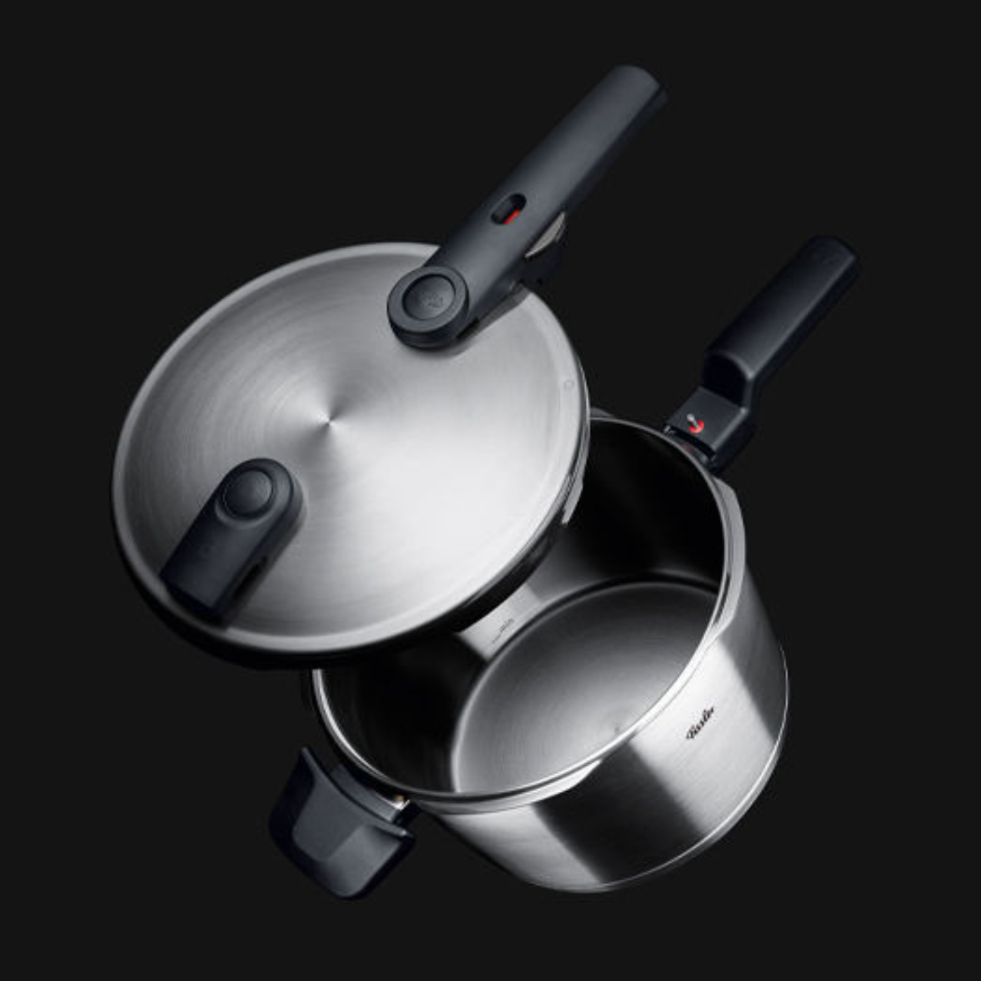Fissler stainless steel pressure cooker with ergonomic black handle, open lid, and sleek German design against a black background.