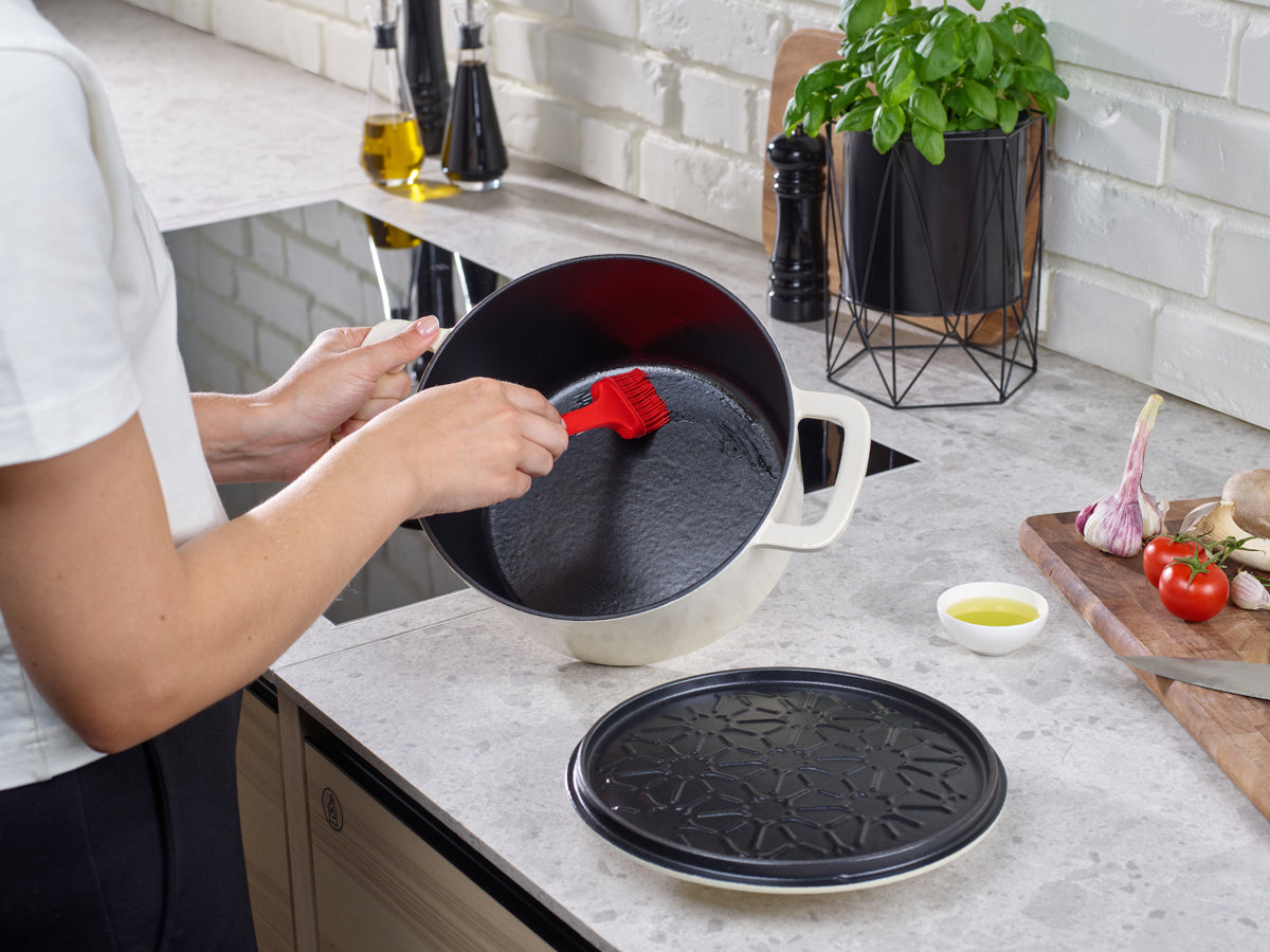 Brush oil in a Fissler Moments cast iron pot. Modern kitchen with vegetables, board, and tool precision "Made in Germany".