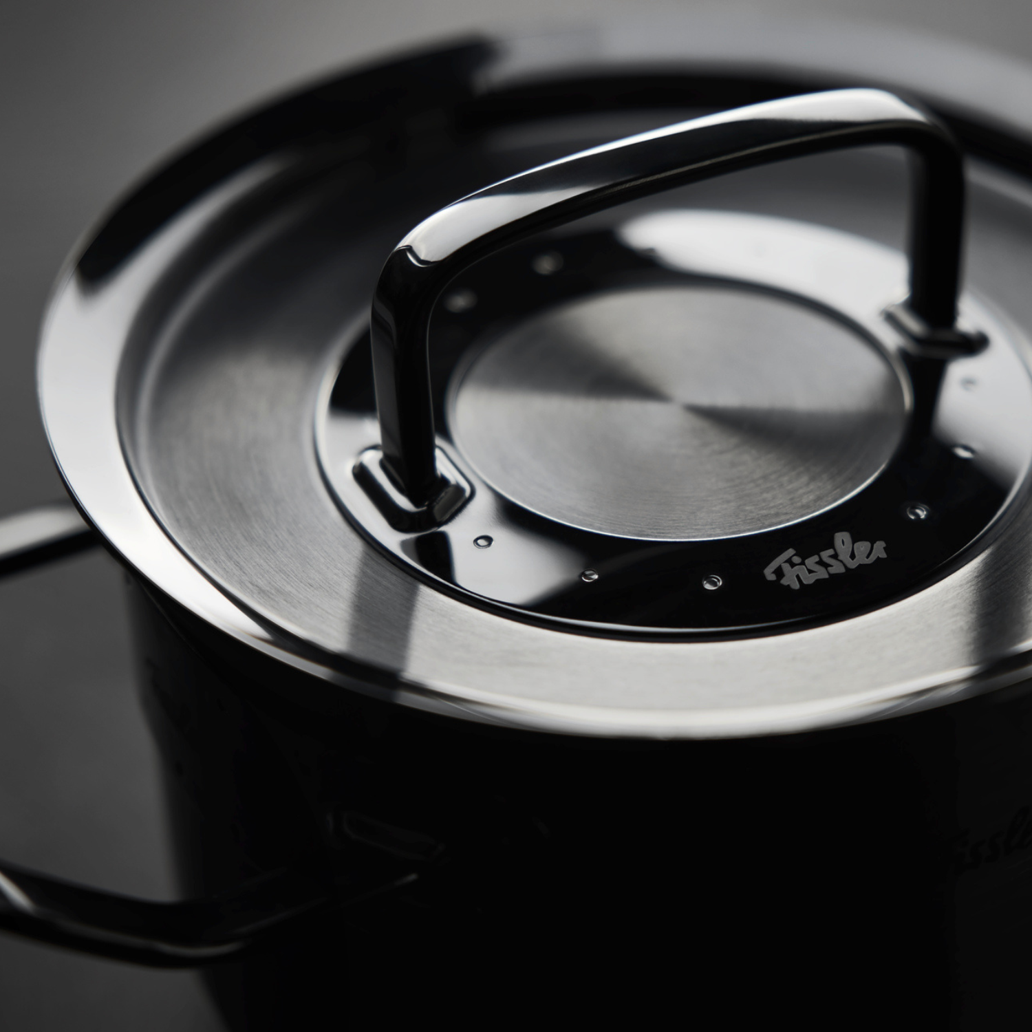 Nahaufnahme eines Fissler-Edelstahltopfs, der unseren präzisionsgefertigten Deckel und Griff zeigt. Auf dem Deckel ist "Fissler" eingraviert.