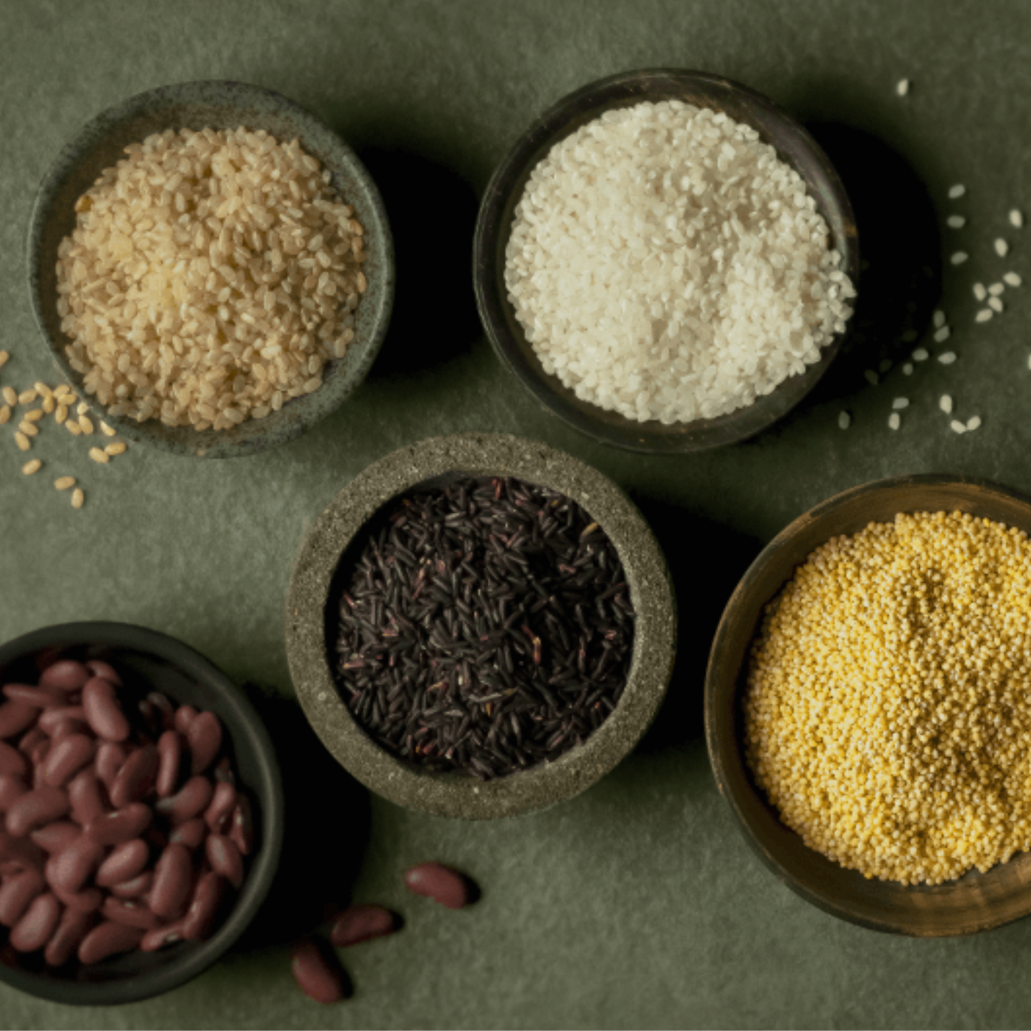 Five bowls with different grains and legumes, presented on a green surface - a perfect addition to Fissler's timeless cookware.