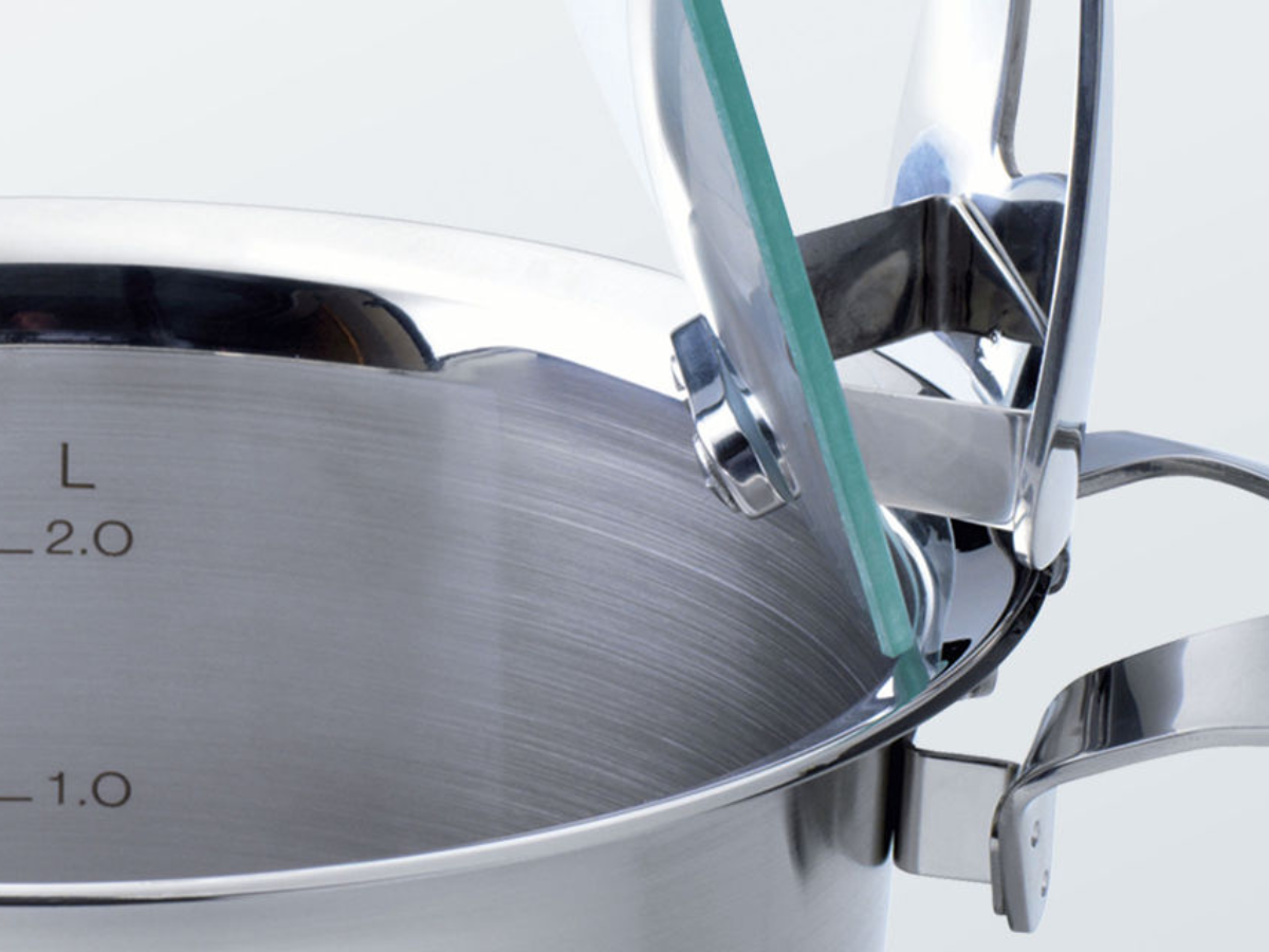 Close-up of a Fissler stainless steel pot with precise measuring marks and an innovative glass hinged lid, made in Germany.