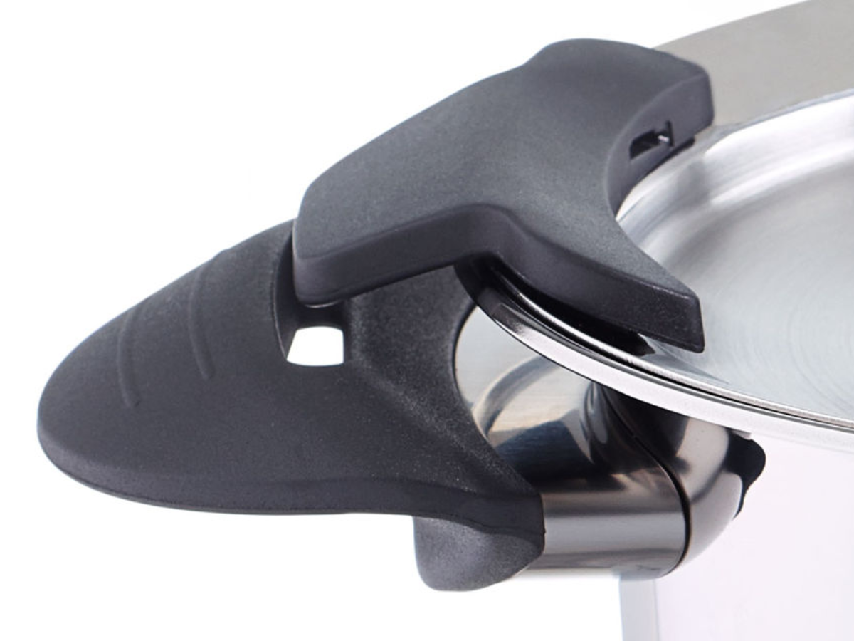 Close-up of a precision-engineered black locking handle on a Fissler stainless steel pressure cooker lid, highlighting the closure mechanism.