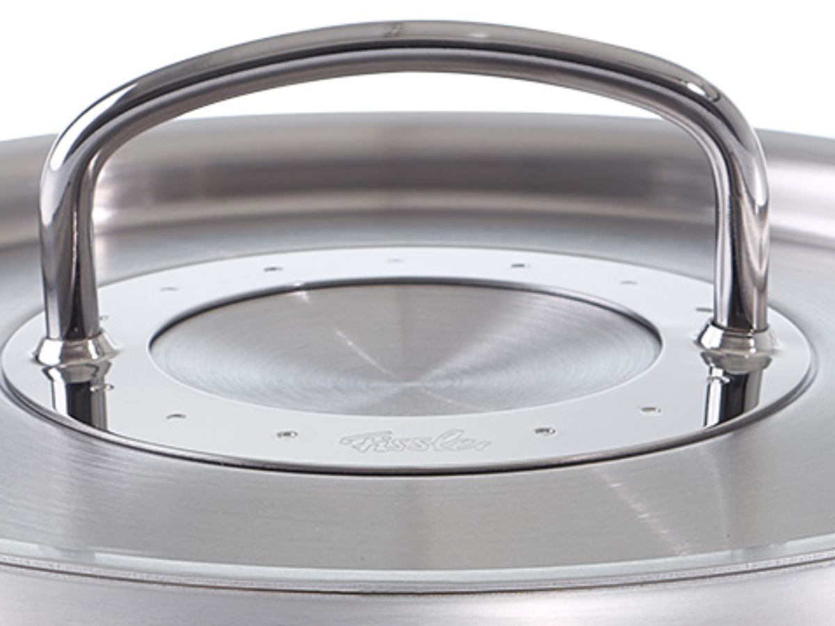 Close-up of a Fissler stainless steel pot lid with a sturdy handle, precise ventilation slots, and the characteristic brushed metal finish.