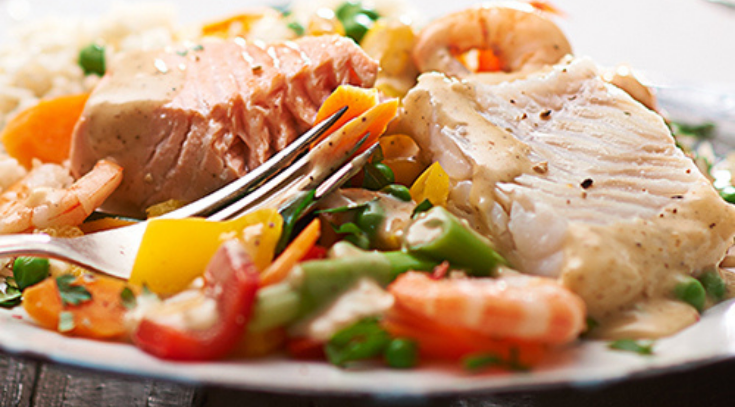 Ein Gourmet-Gericht mit Fischfilets und Garnelen in Sahnesoße, serviert mit Reis - zubereitet mit dem Präzisionskochgeschirr von Fissler.