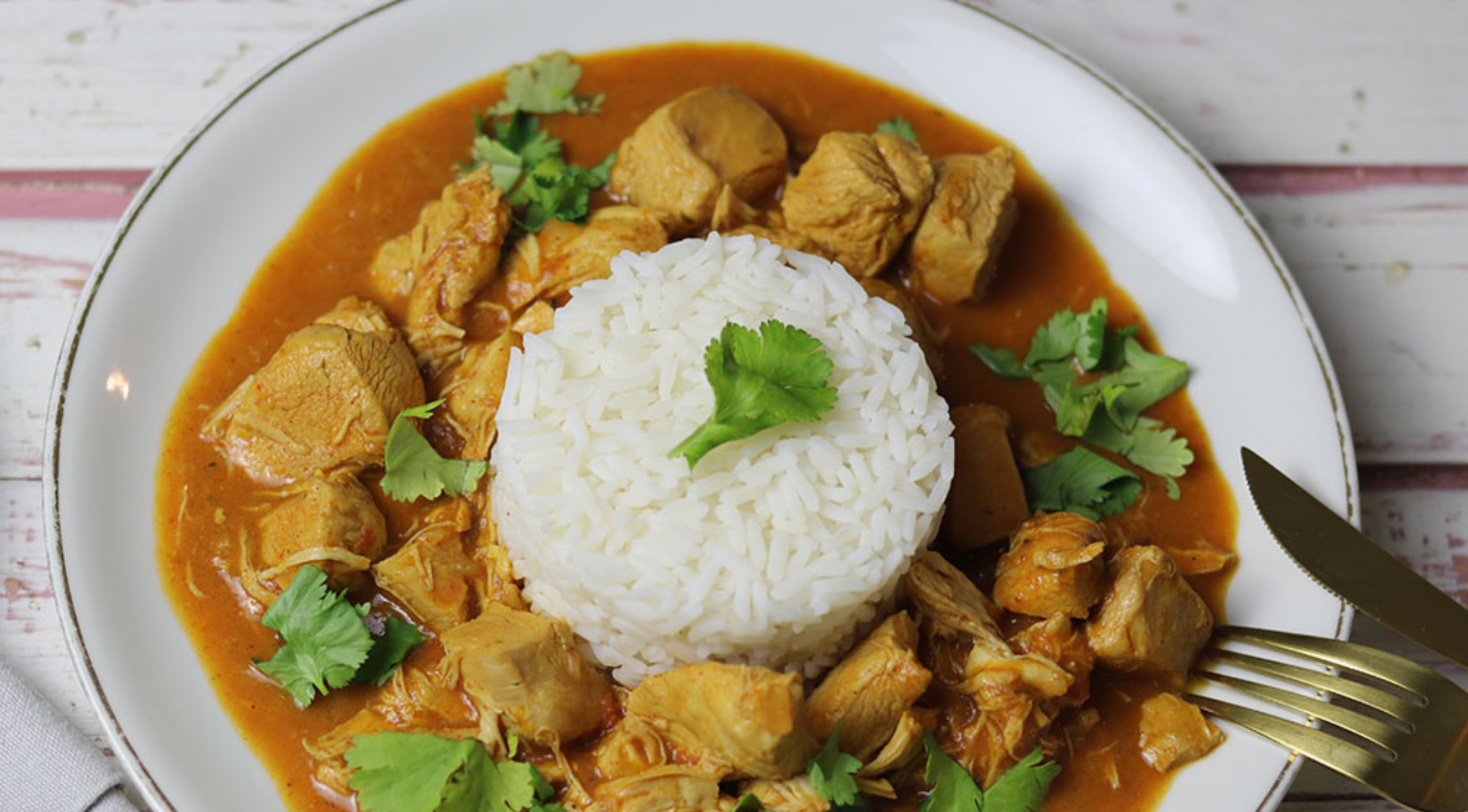 Ein wunderschön angerichtetes Hühnercurry mit Reis, serviert mit dem Präzisionsbesteck von Fissler - wie geschaffen für perfekte Essensmomente.