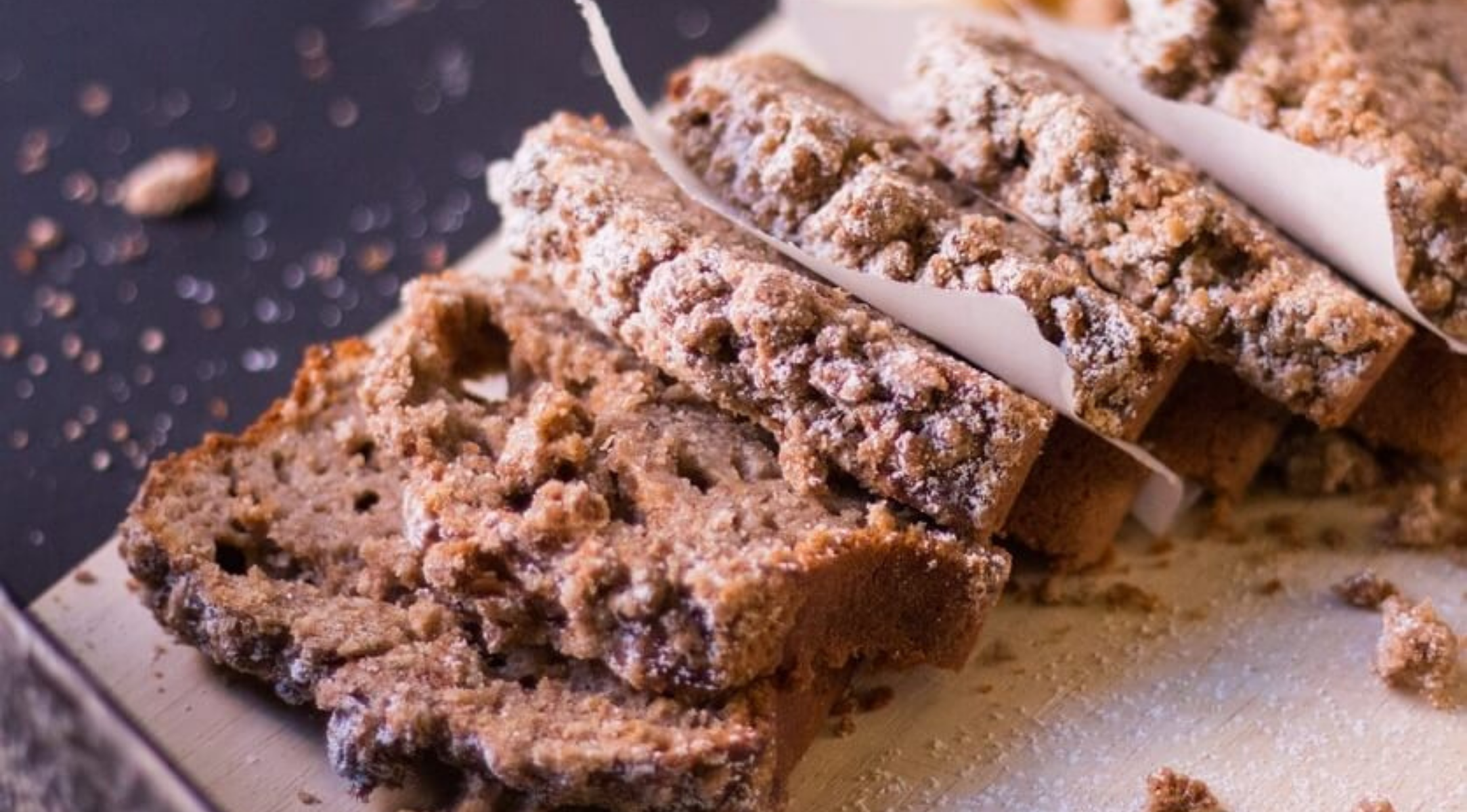 In Scheiben geschnittenes Zimtkrumenbrot auf Holz, getrennt durch Pergament, mit gestreuten Krümeln - mit Fissler-Qualität und Präzision hergestellt.