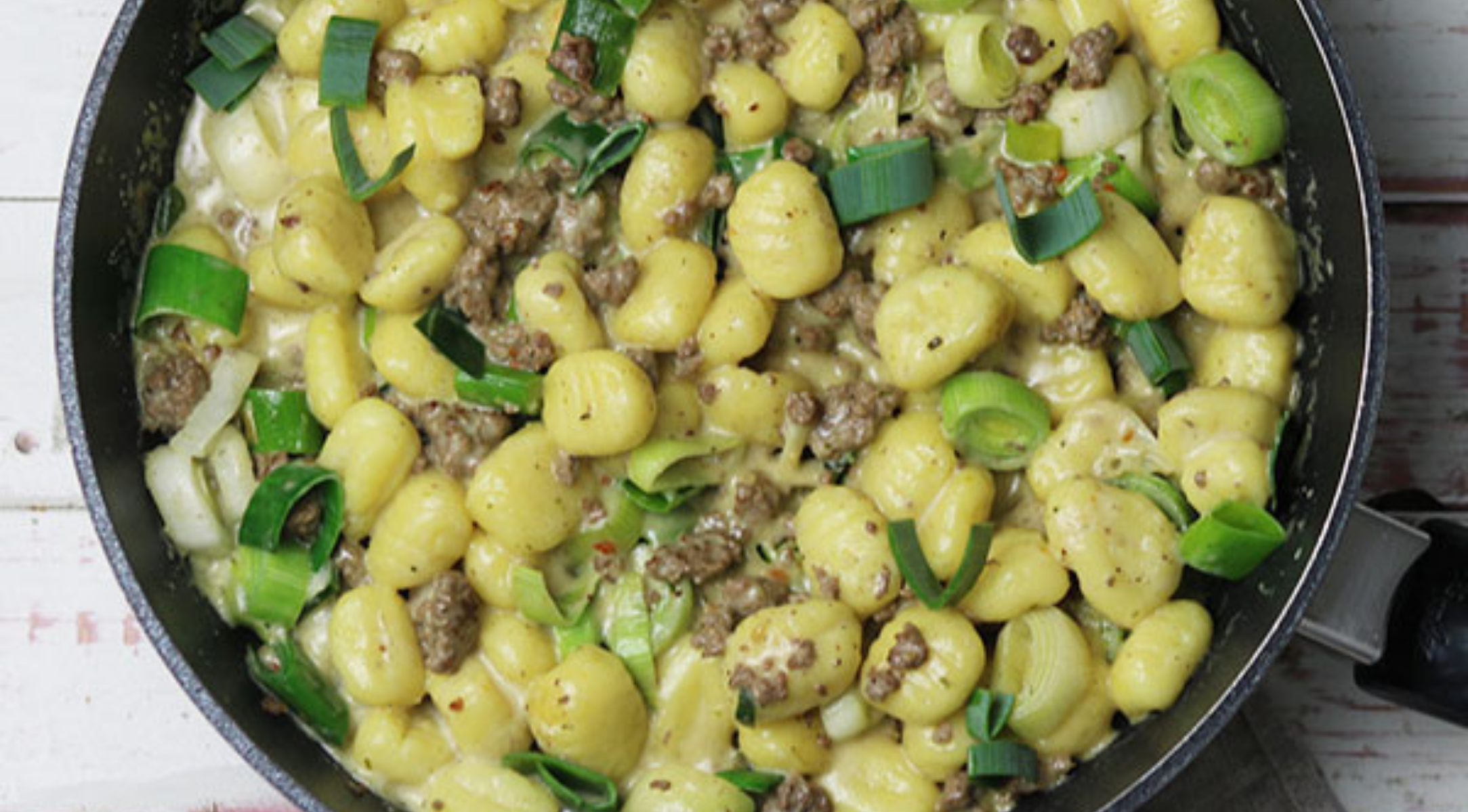 Gnocchi, Wurst und Frühlingszwiebeln in einer cremigen Sauce, serviert in einer präzisionsgefertigten Fissler-Pfanne.