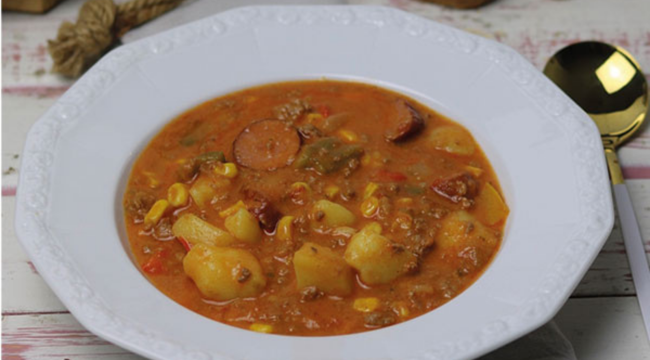 Eine weiße Schüssel mit einem kräftigen Eintopf mit Wurst, Kartoffeln und Gemüse in reichhaltiger Brühe - zubereitet mit dem deutschen Präzisionskochgeschirr von Fissler.