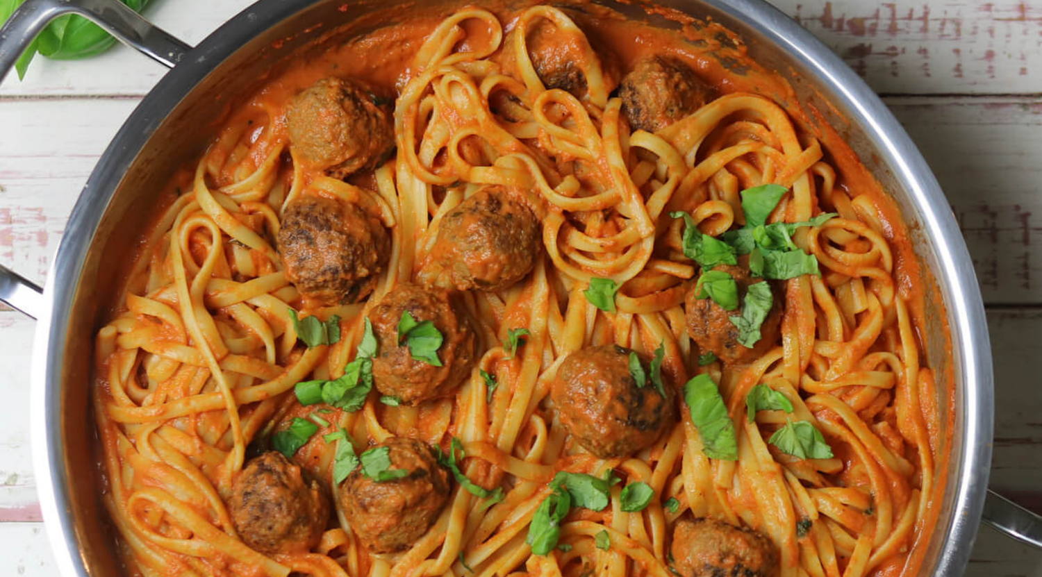 Fissler-Edelstahlpfanne mit Fettuccine und Fleischbällchen in cremiger Tomatensauce, verfeinert mit frischem Basilikum.