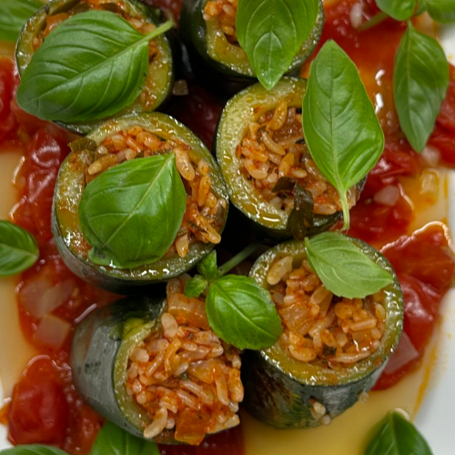 Gefüllte Zucchini mit Reis und Kräutern, garniert mit Basilikum auf einer kräftigen Tomatensauce, elegant angerichtet im hochwertigen Fissler-Kochgeschirr.