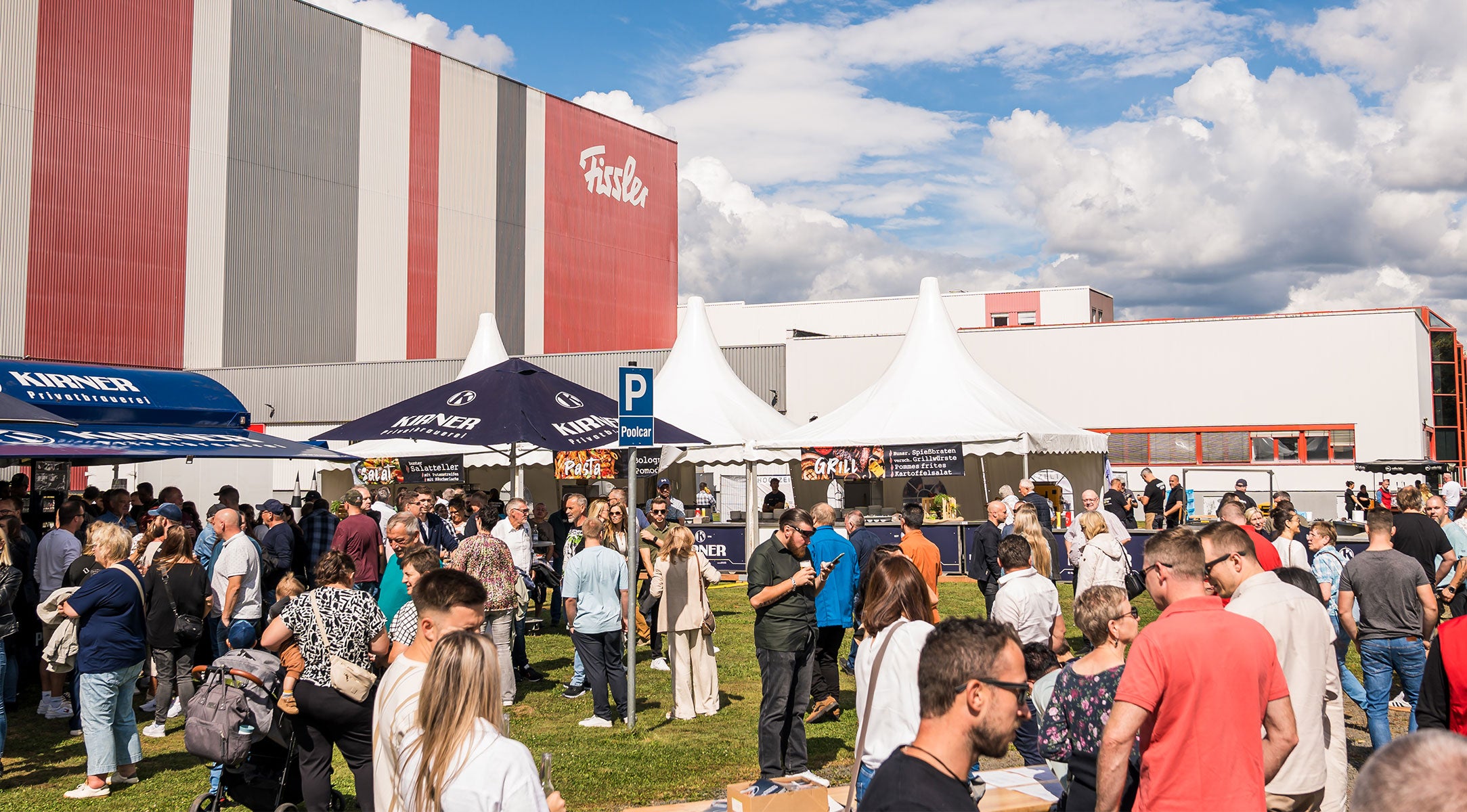 Neben dem ikonischen Fissler-Gebäude genießen die Besucher Gourmet-Essen und entdecken unter sonnigen Zelten und Schirmen hochwertige deutsche Kochgeräte.