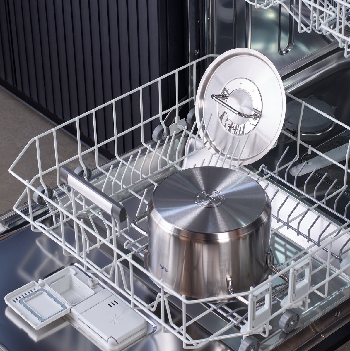 A Fissler Pure Collection stainless steel pot with lid sits in the dishwasher, highlighting its German-made, dishwasher-safe quality.