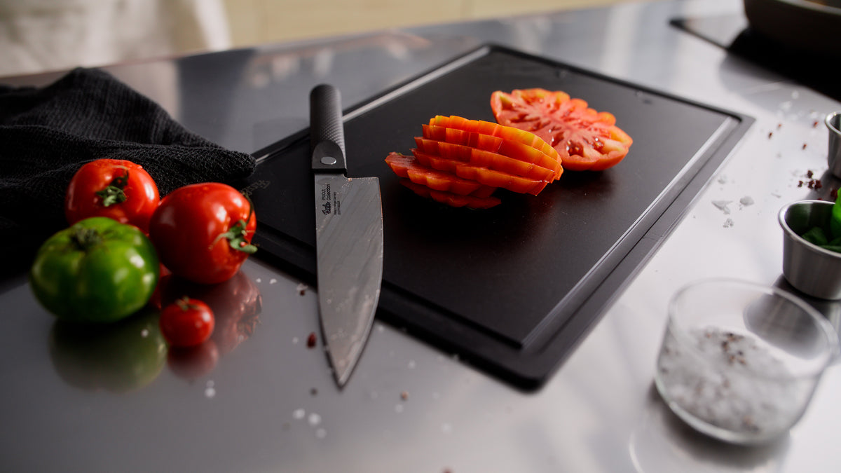 Fissler ProCut Kochmesser 20cm auf schwarzem Brett mit Heirloom-Tomaten, Salz und Tassenpräzision made in Germany seit 1845.