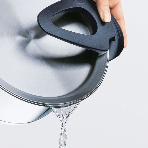 Eine Hand gießt Wasser aus einem Fissler-Edelstahltopf mit innovativem Siebdeckel aus, der den Inhalt sicher im Inneren hält.