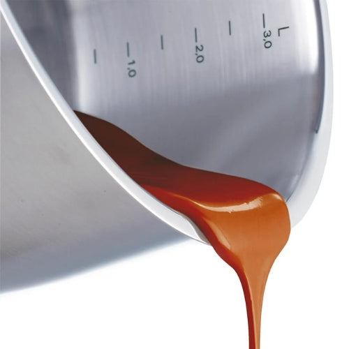 Die Karamellsauce wird aus einer Fissler-Edelstahlschüssel gegossen, die mit präzisen Messmarkierungen für perfekte Ergebnisse sorgt.