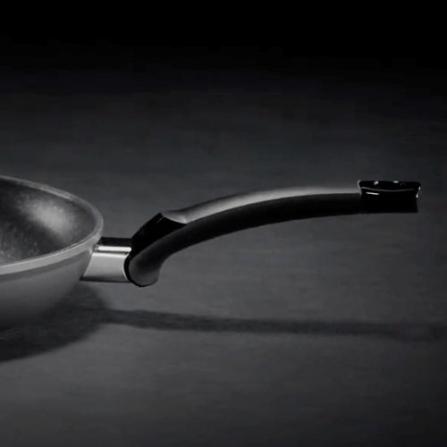 Nahaufnahme einer Fissler Bratpfanne mit ergonomischem schwarzem Griff, die deutsche Präzision vor einem schlichten, dunklen Hintergrund zeigt.