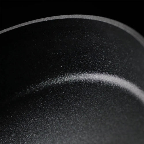 Nahaufnahme einer Fissler Antihaft-Bratpfanne, die ihre glatte, fachmännisch gefertigte Oberfläche und ihre geschwungenen Kanten in eleganten Details zeigt.