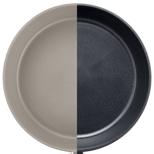 Eine Fissler Bratpfanne, vertikal geteilt: linke Seite hellgrau, rechte dunkelgrau, was die innovative deutsche Antihaftbeschichtung hervorhebt.