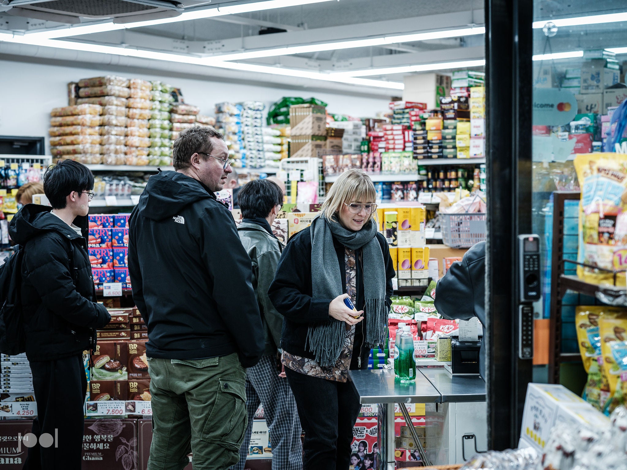 Kunden stehen Schlange in einem hell beleuchteten Fachgeschäft, in dem die Premium-Kochgeschirrkollektion von Fissler präsentiert wird. Die Frau ganz vorne wählt präzise gefertigte Töpfe und Pfannen aus Edelstahl aus, während andere zwischen den kunstvoll arrangierten Regalen mit Fissler-Schnellkochtöpfen und langlebigen Küchenaccessoires auf ihre Reihe warten – jedes einzelne Produkt steht für deutsche Innovation und zeitloses Design.