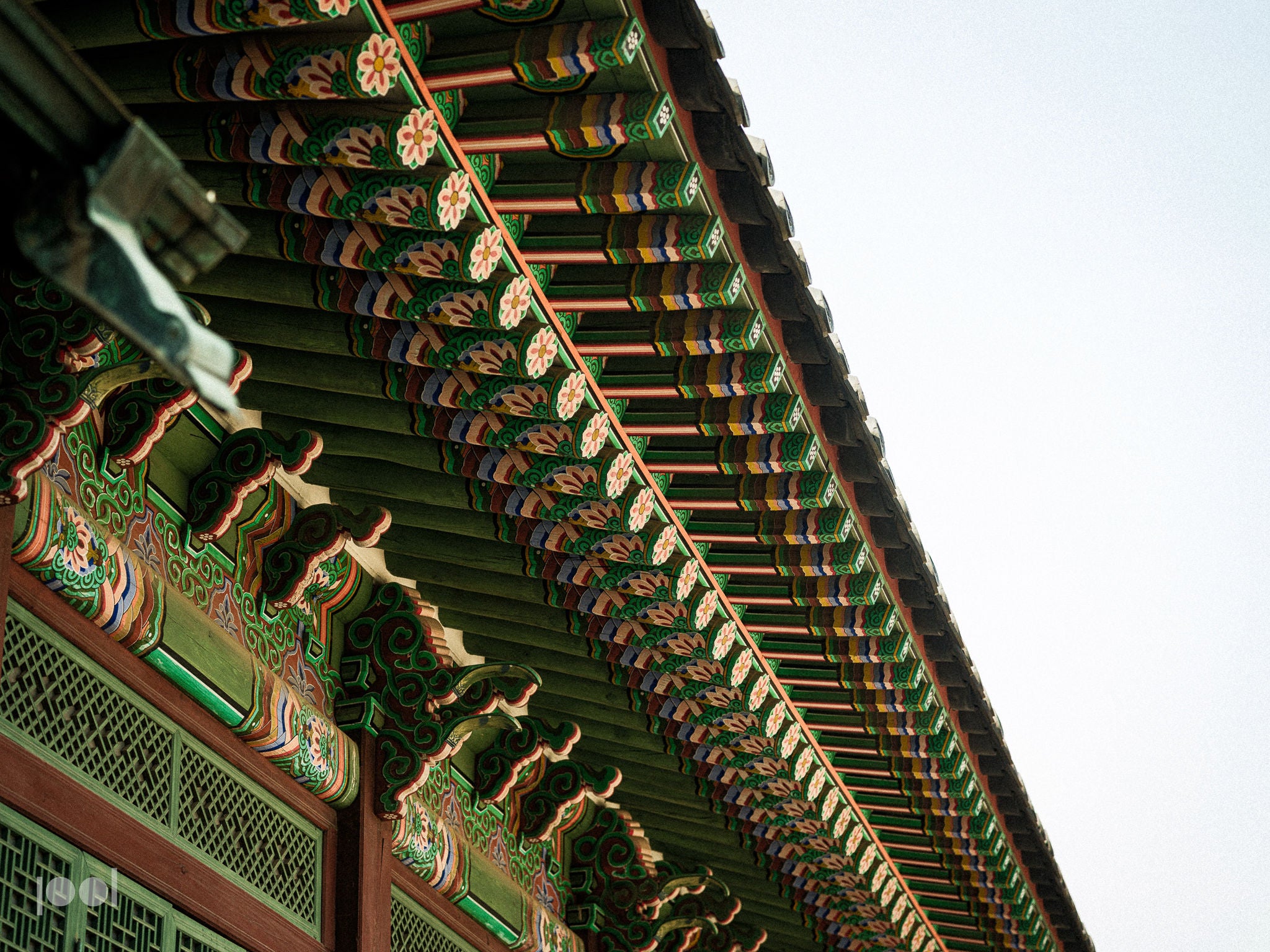 Präzision und Kunstfertigkeit vereinen sich in dieser Nahaufnahme der farbenfrohen, kunstvoll verzierten Dachvorsprünge eines traditionellen koreanischen Gebäudes, wo sich detailreiche Holzschnitzereien und Muster elegant vor einem klaren Himmel abheben – ein inspirierendes Beispiel für handwerkliches Können, das an Fisslers Bekenntnis zu hochwertiger deutscher Ingenieurskunst in unseren Kochgeschirrkollektionen erinnert.
