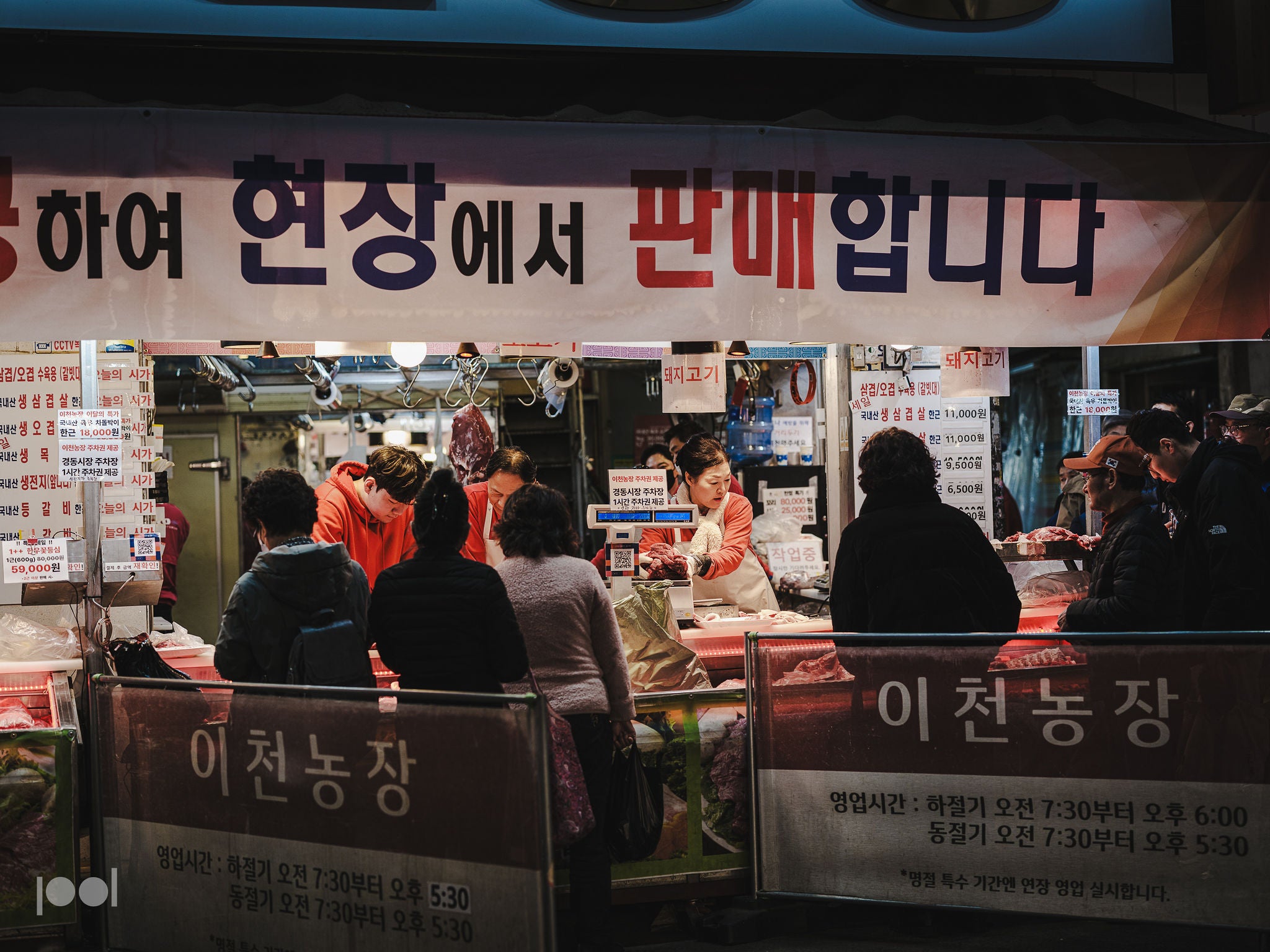 Shoppers select fresh meat at a lively Korean night market, illuminated by bright lights beneath a sign with Korean text. The vibrant atmosphere highlights the importance of quality tools—like Fissler’s precision-engineered stainless steel cookware—for preparing meals with excellence and enduring style.